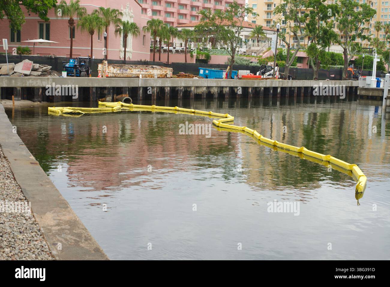Tranquillo lungomare urbano che mostra una barriera galleggiante gialla accanto al molo, evidenziando il controllo dell'inquinamento e le misure di sicurezza delle acque. Uso editoriale solo maggio Foto Stock