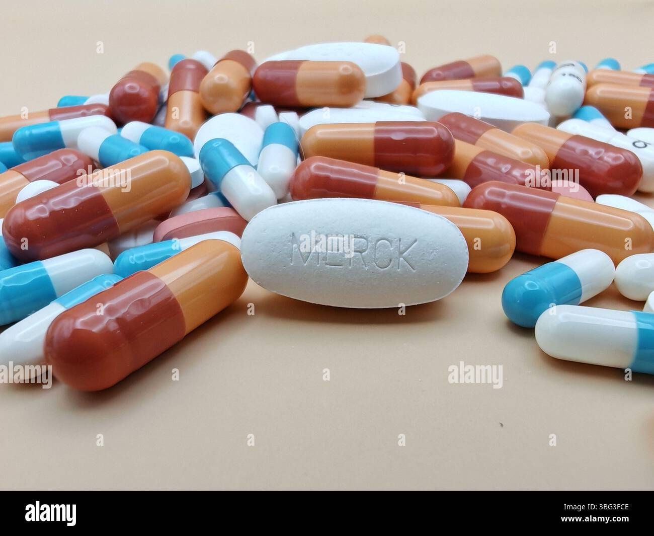 Pillola bianca con impronta MERCK posta su un mucchio di compresse e capsule colorate in una vista farmaceutica. Foto Stock