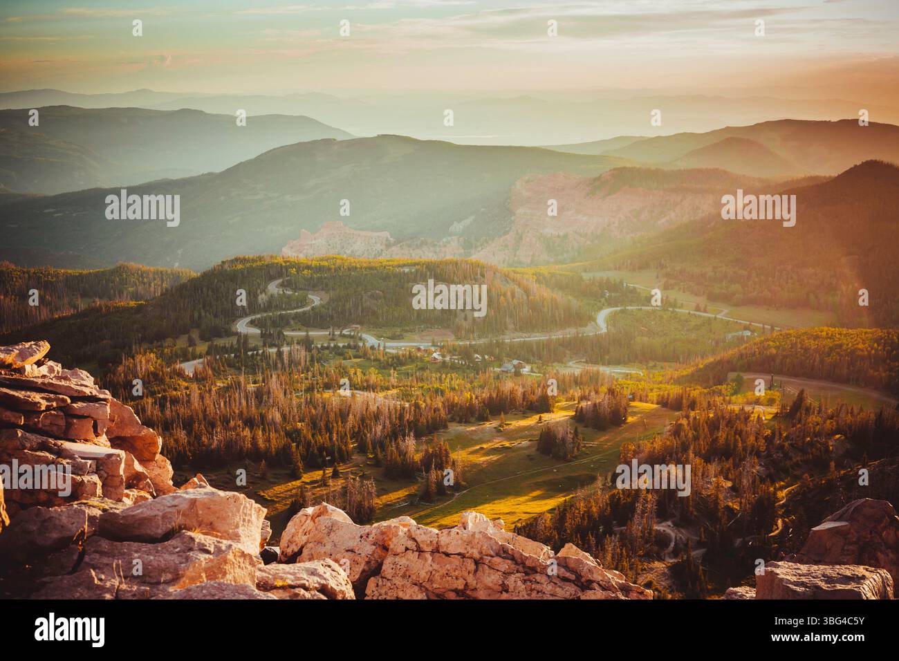 Paesaggio di montagna panoramico all'ora d'oro con strade tortuose, valli boscose e morbida foschia, evocando pace, solitudine, e bellezza naturale Foto Stock