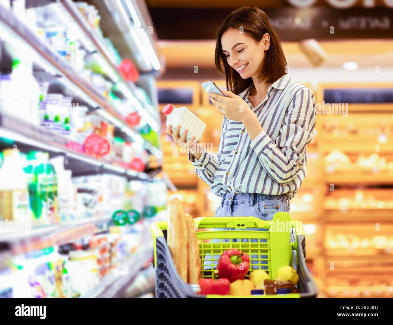 Donna che esegue la scansione del codice sui prodotti utilizzando lo smartphone Foto Stock