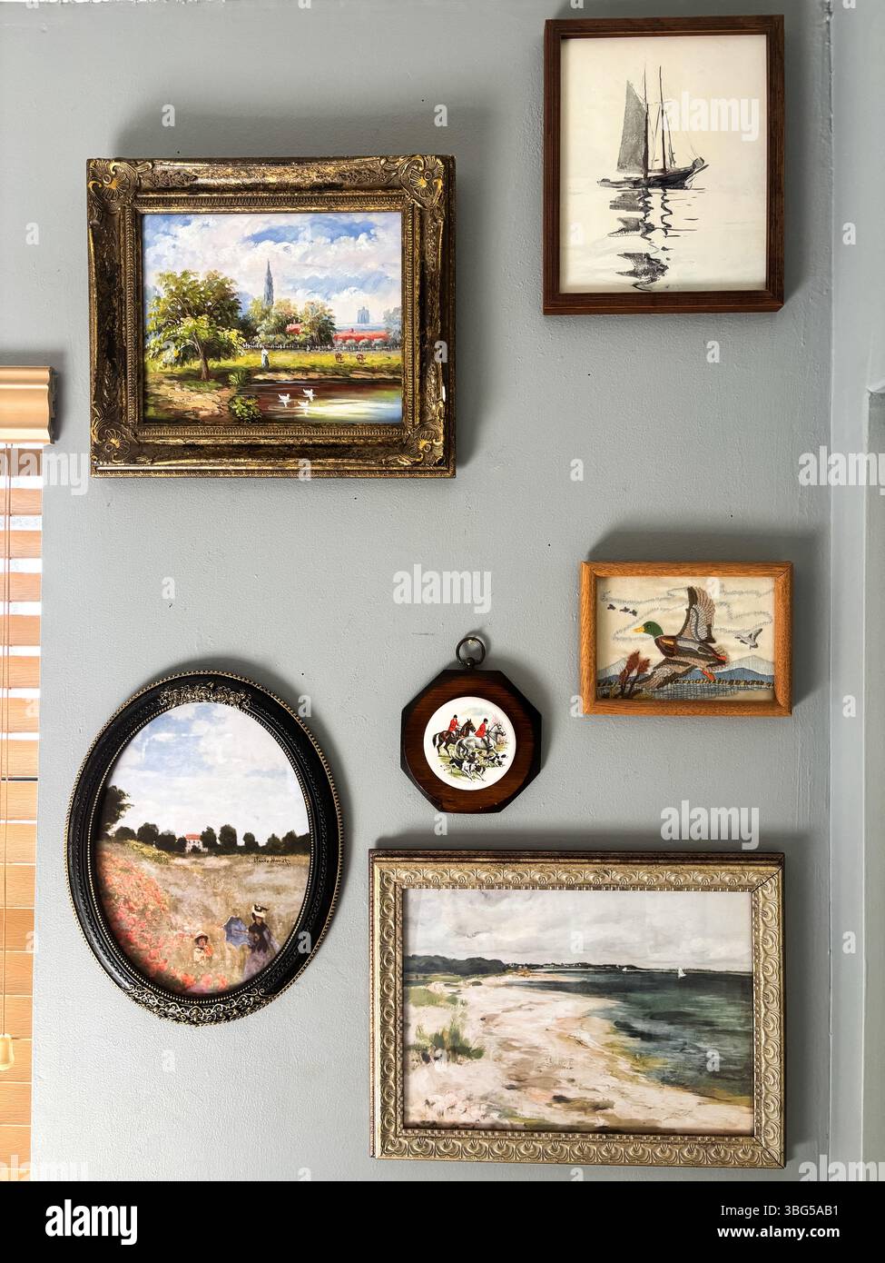 Eclettico muro della galleria con opere d'arte vintage incorniciate, tra cui paesaggi, paesaggi marini e illustrazioni di animali. Presa nel maggio 2025 a Miami, Florida. Foto Stock