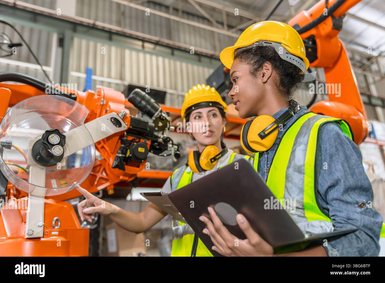 formazione di ingegneri robotici, tecnici che lavorano nella moderna fabbrica industriale robot braccio di saldatura operatore di controllo della macchina Foto Stock