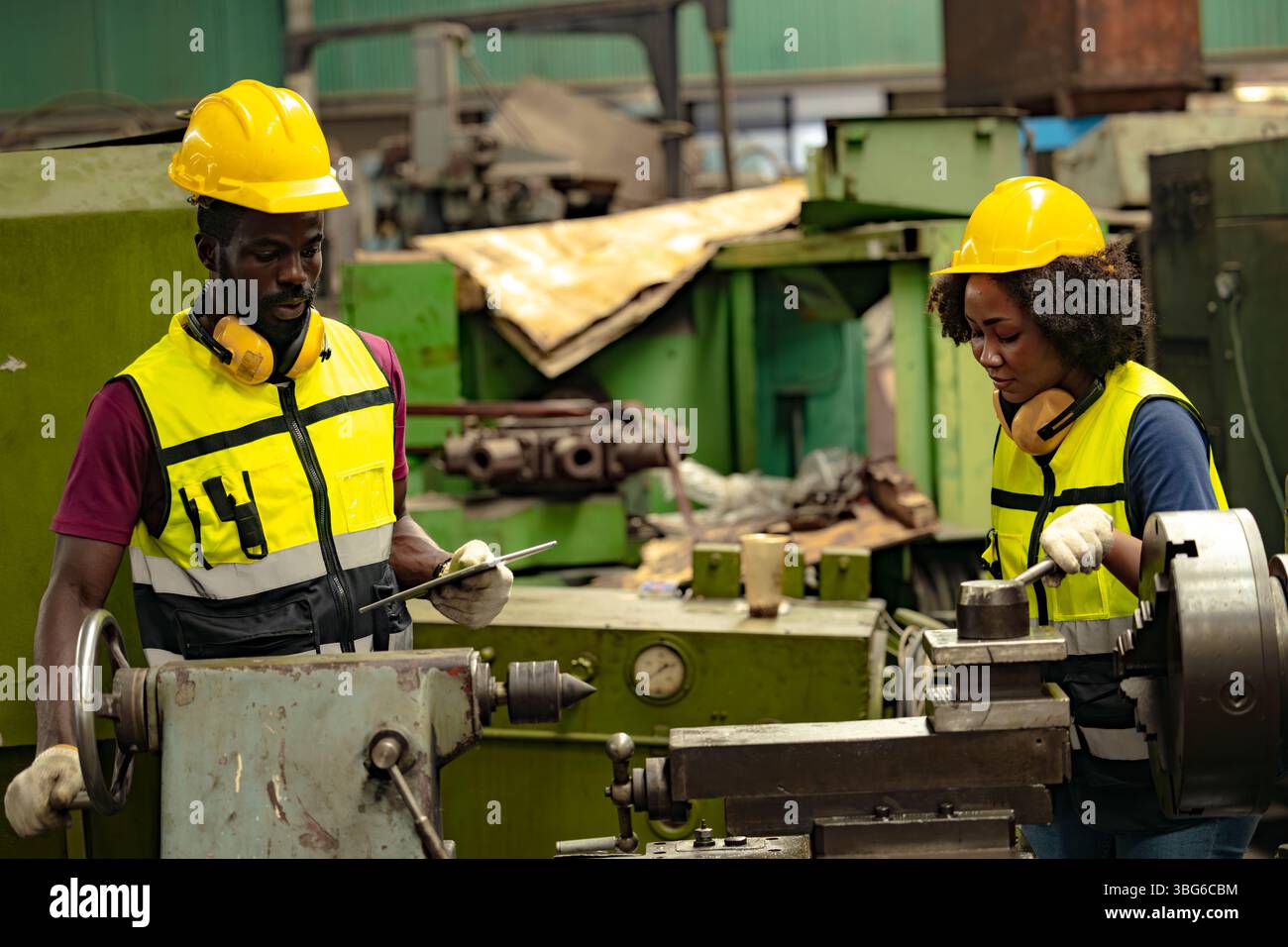 Uomo nero africano tecnico professionista ingegnere persone lavoratori in formazione industria pesante controllo operare fresatrice per giovani donne Foto Stock