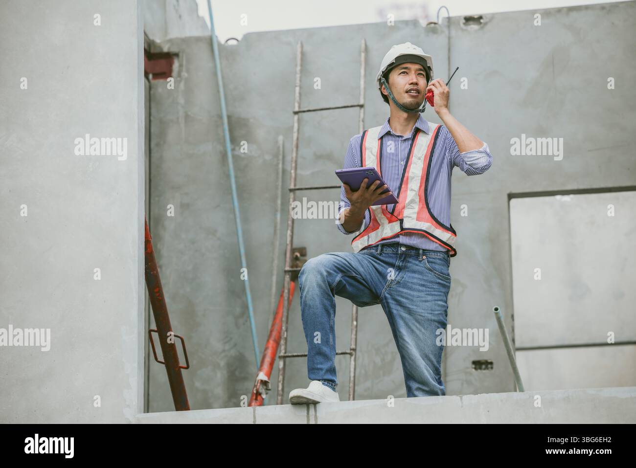 Ingegnere asiatico che supervisiona il progetto di costruzione in cantiere, costruttore professionista che lavora Foto Stock