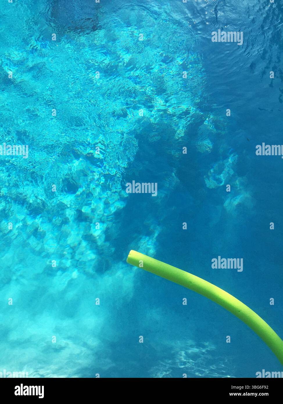Gli spaghetti verdi della piscina galleggiano in limpide acque blu ondulate Foto Stock