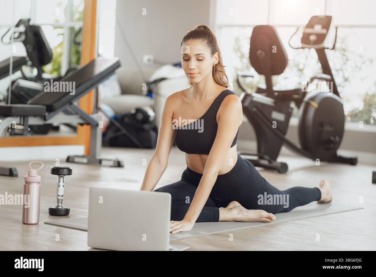 Formazione online per il settore sanitario. Young Fit Woman che si allena al Gym Sport Club, guardando un video tutorial sul laptop Foto Stock