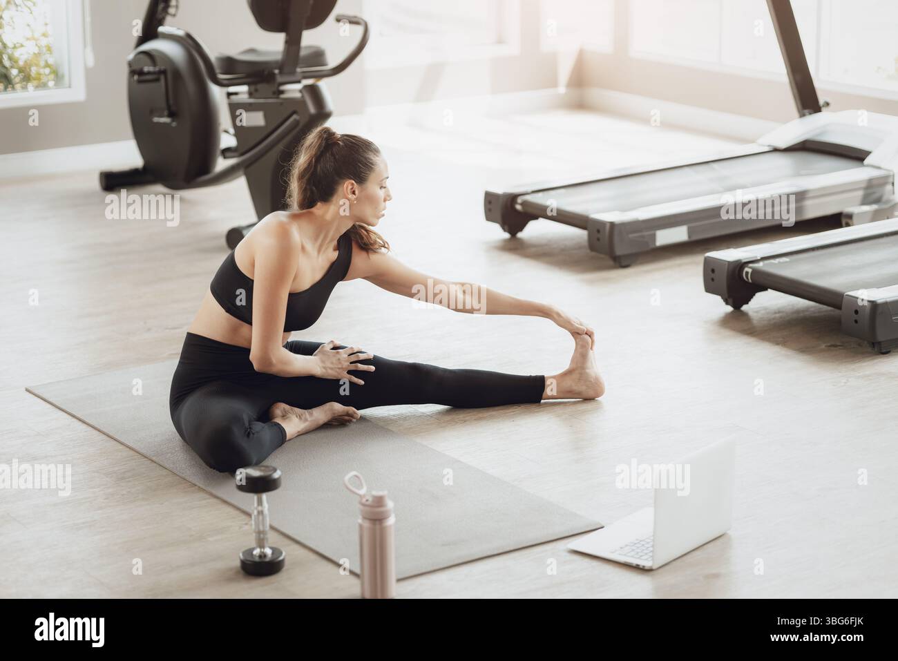 Formazione online per il settore sanitario. Young Fit Woman che si allena al Gym Sport Club, guardando un video tutorial sul laptop Foto Stock