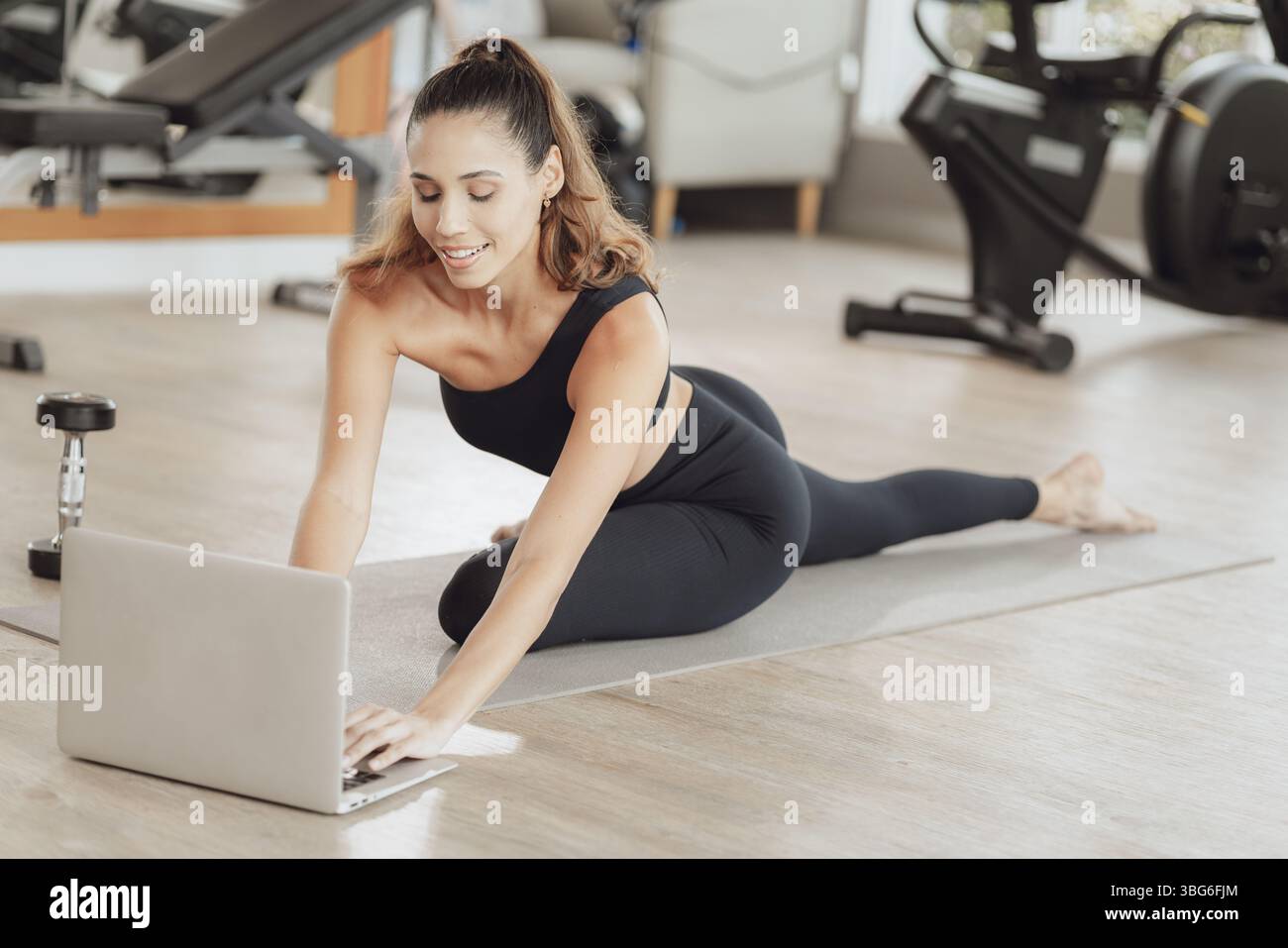 Formazione online per il settore sanitario. Young Fit Woman che si allena al Gym Sport Club, guardando un video tutorial sul laptop Foto Stock