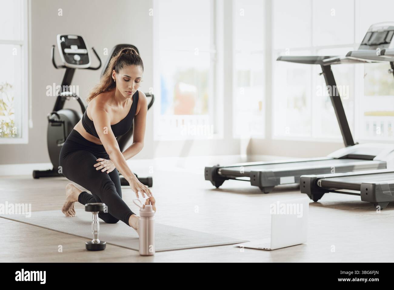 Formazione online per il settore sanitario. Young Fit Woman che si allena al Gym Sport Club, guardando un video tutorial sul laptop Foto Stock