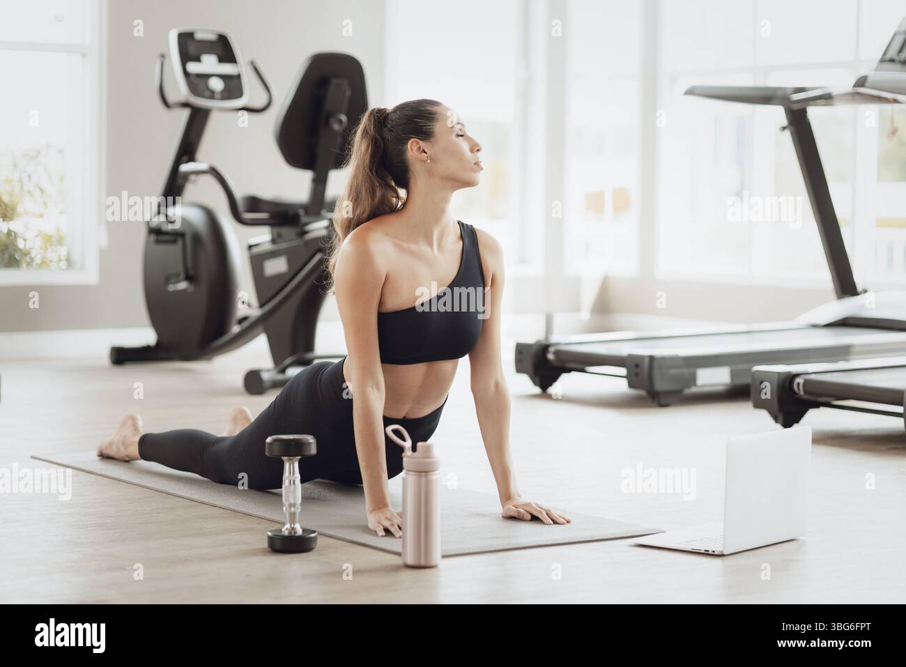 Formazione online per il settore sanitario. Young Fit Woman che si allena al Gym Sport Club, guardando un video tutorial sul laptop Foto Stock