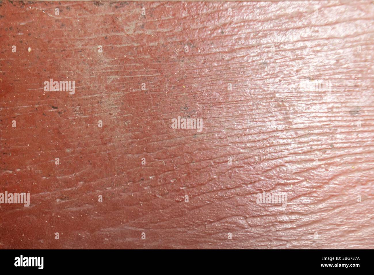 Questa immagine ravvicinata mostra la trama e la grana intricate di una superficie in legno rosso intemprato, evidenziando la sua bellezza rustica e il suo fascino naturale. Foto Stock