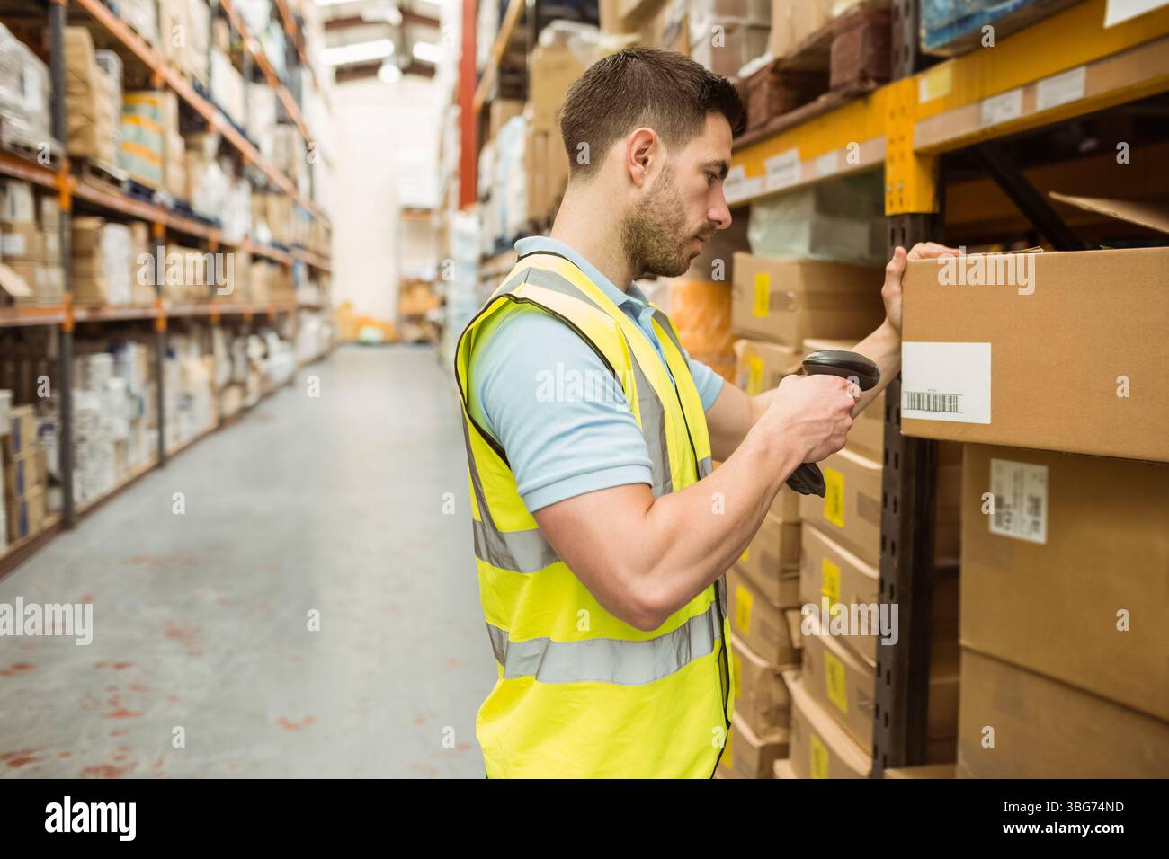 Lavoratore maschile che indossa un giubbotto di sicurezza utilizzando scanner che scansiona codici a barre su scatole in magazzino, spazio di copia Foto Stock