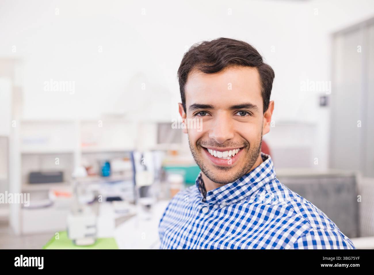 Strumento ottico posizionato su un tappeto verde sulla scrivania in un ambiente di ufficio luminoso con scaffalature bianche Foto Stock
