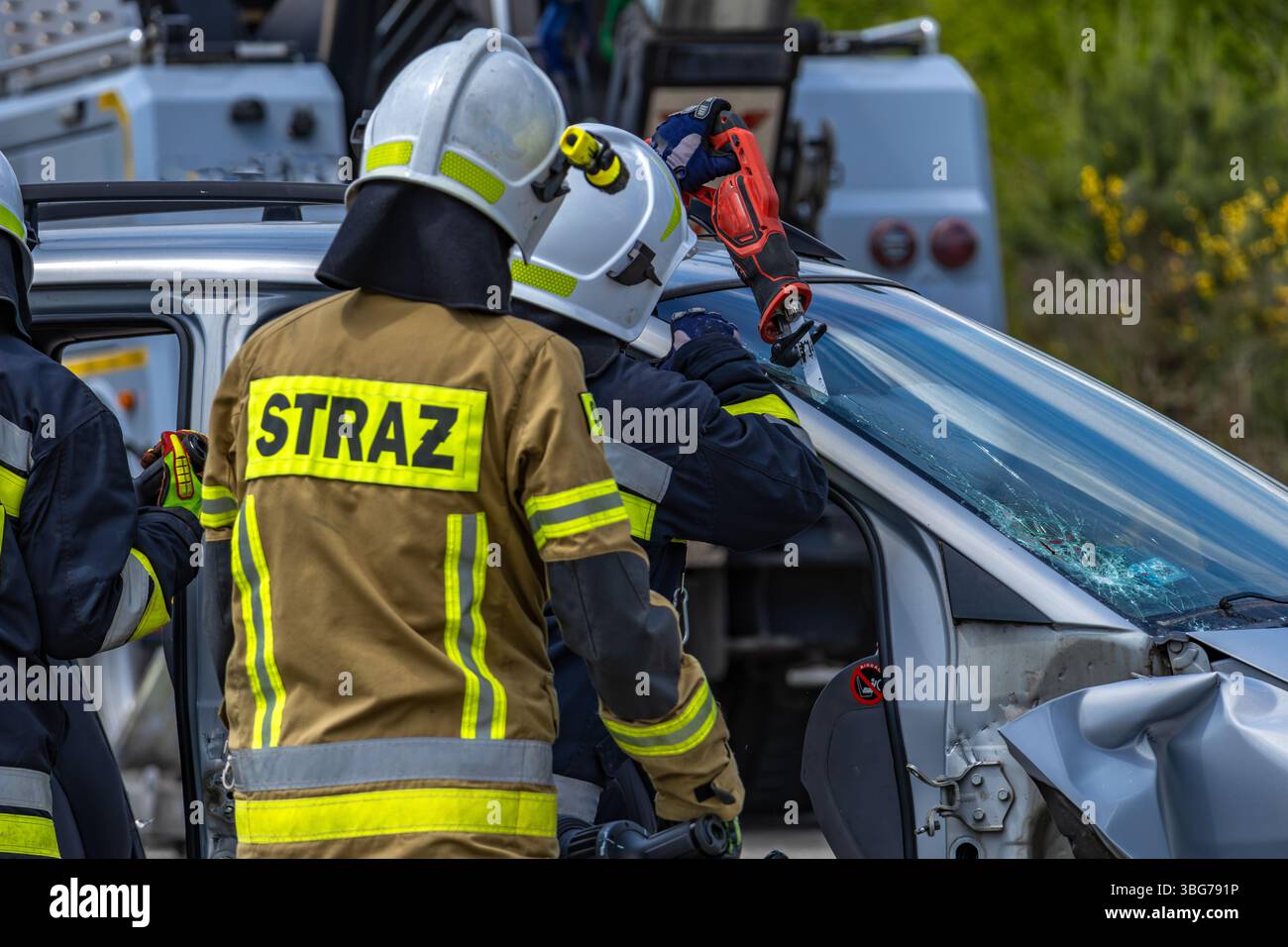 I vigili del fuoco usano le forbici per tagliare il parabrezza di un'autovettura coinvolta in un incidente. Foto Stock