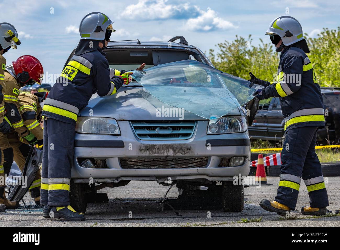 I vigili del fuoco usano le forbici per tagliare il parabrezza di un'autovettura coinvolta in un incidente. Foto Stock