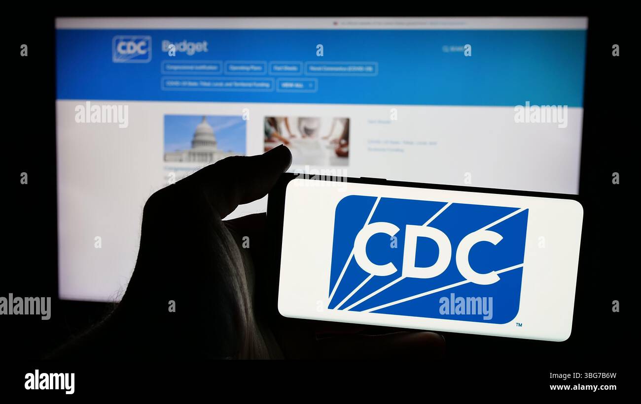 Stoccarda, Germania - 01-28-2025: Persona che tiene un telefono cellulare con il logo dei centri per il controllo e la prevenzione delle malattie (CDC) sullo schermo Foto Stock