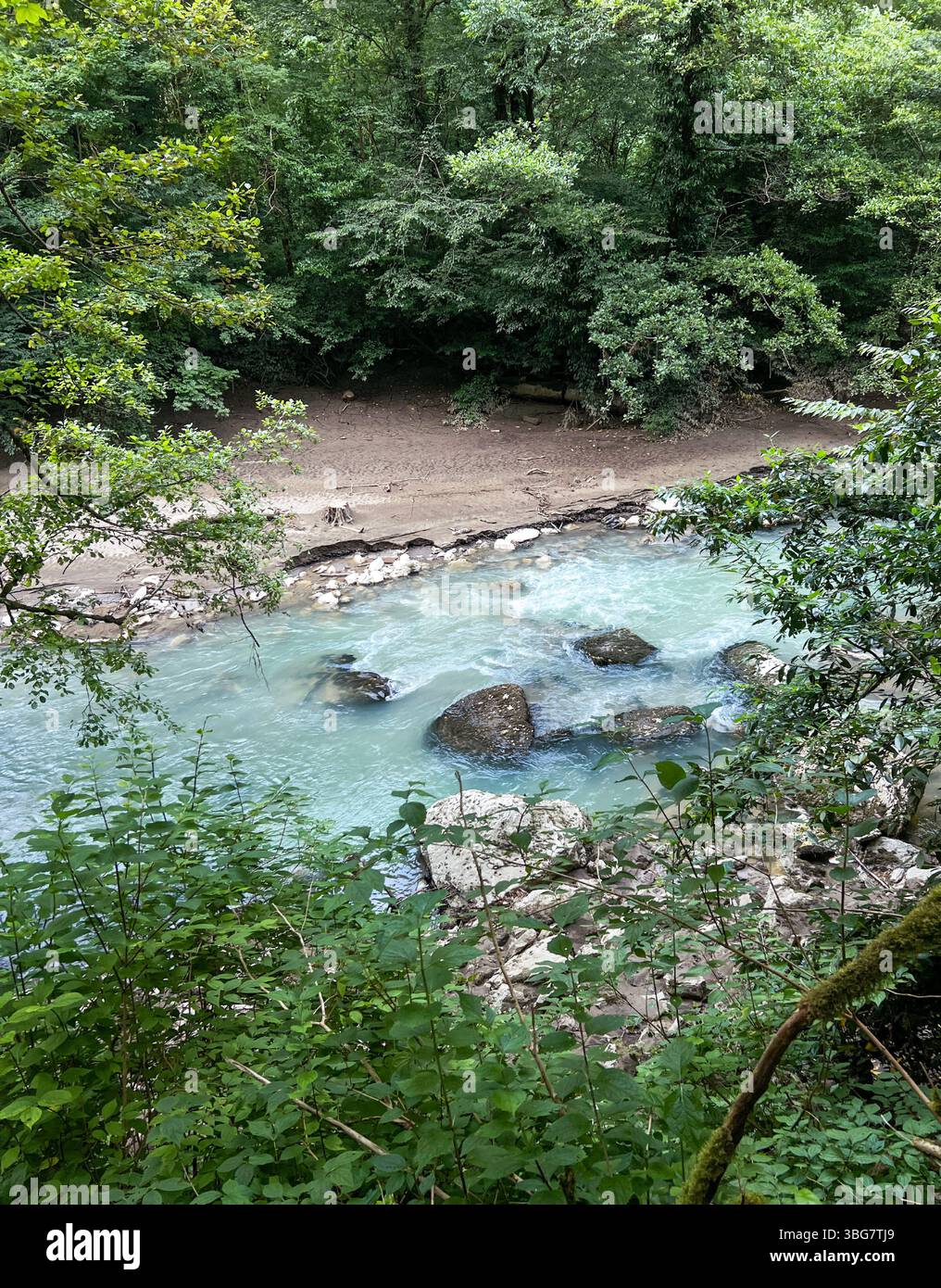 fiume calmo con acque turchesi con rocce lisce e sponde sabbiose in una foresta vibrante, momenti tranquilli nella natura e avventure all'aria aperta, bellezza Foto Stock