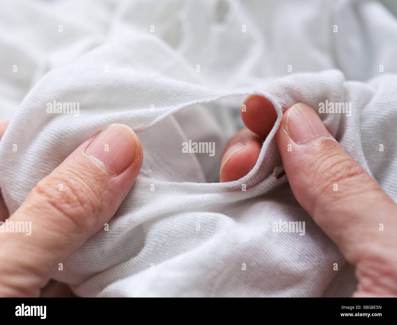 Un uomo che ispeziona una maglietta strappata. Primo piano. Foto Stock