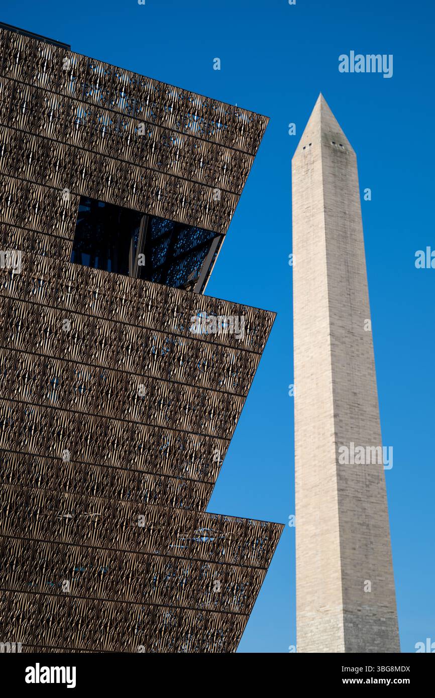 WASHINGTON DC - lo Smithsonian National Museum of African American History and Culture si erge in primo piano con il Washington Monument sullo sfondo del National Mall. Il caratteristico esterno in metallo color bronzo del museo, progettato dall'architetto David Adjaye e inaugurato nel settembre 2016, crea un contrasto sorprendente con l'obelisco in marmo bianco in onore del primo presidente americano. Questa vista cattura il dialogo architettonico tra il più recente museo Smithsonian della nazione e uno dei suoi monumenti più antichi. Foto Stock