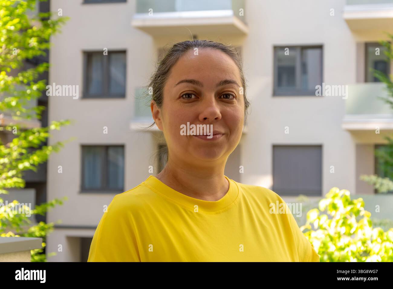Una donna di 40-45 anni in piedi sul balcone o sulla terrazza di un condominio Foto Stock