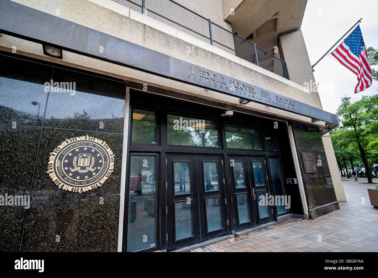 Ingresso del quartier generale dell'FBI sulla Pennsylvania Avenue a Washington DC | WASHINGTON, D.C. — L'ingresso dell'edificio J. Edgar Hoover dell'FBI sulla Pennsylvania Avenue, sede del Federal Bureau of Investigation nel centro di Washington. Costruito tra il 1967 e il 1975 secondo i progetti dell'azienda di Chicago Charles F. Murphy and Associates, il complesso brutalista ha ricevuto il suo nome ufficiale attraverso la Public Law 92-520, firmata dal presidente Nixon il 4 maggio 1972 — solo due giorni dopo la morte di Hoover e più di tre anni prima che il presidente Ford dedicasse l'edificio il 30 settembre 1975. L'ultimo piano della struttura Foto Stock