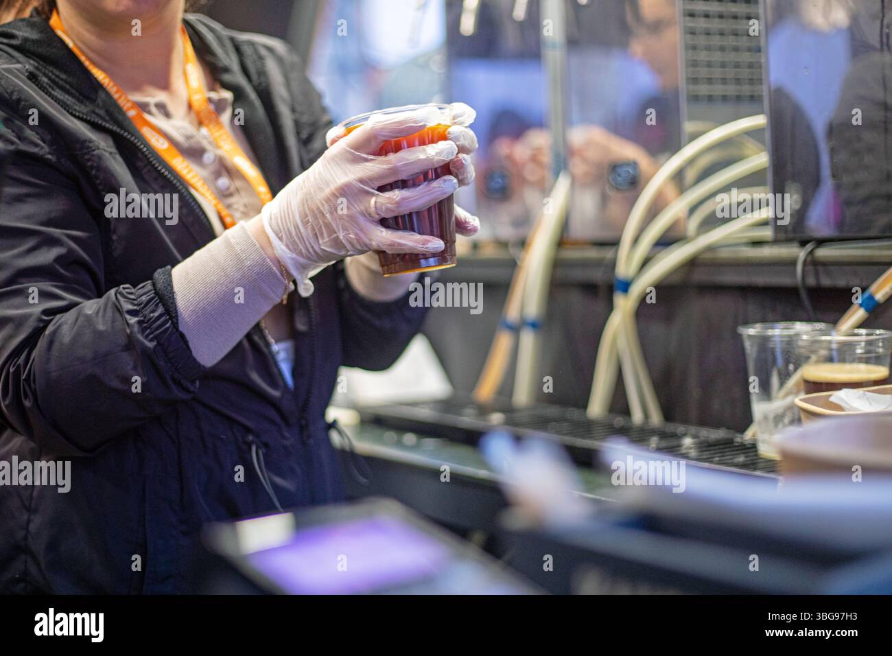 vendere in un bicchiere di plastica trasparente monouso di materiali riciclabili birra fresca da bere o kvass con guanti. cibo di strada Foto Stock