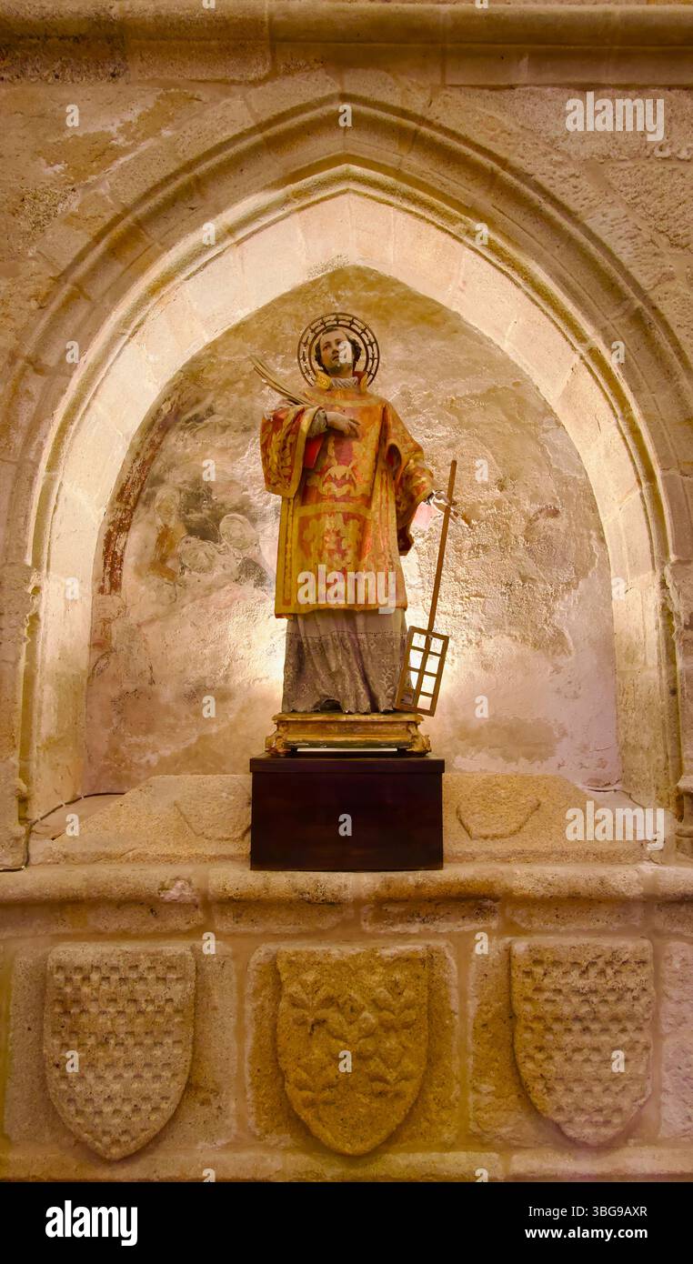 Scultura di San Lorenzo che tiene un gridiron in un'alcova con stemmi scolpiti in pietra Concattedrale di Santa Maria Caceres Estremadura Spagna Foto Stock