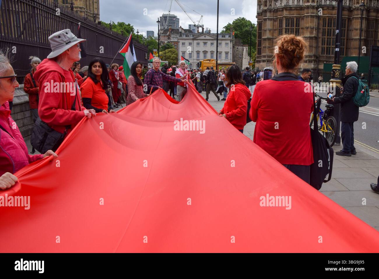 Londra, Regno Unito. 4 giugno 2025. I manifestanti pro-palestinesi si riuniscono fuori dalle camere del Parlamento chiedendo un embargo sulle armi contro Israele, che Israele interrompa i suoi attacchi a Gaza e che gli aiuti vengono erogati alla popolazione affamata. Centinaia di manifestanti tenevano un lungo tessuto rosso intorno al parlamento, simboleggiando le "linee rosse” attraversate da Israele. Crediti: Vuk Valcic/Alamy Live News Foto Stock