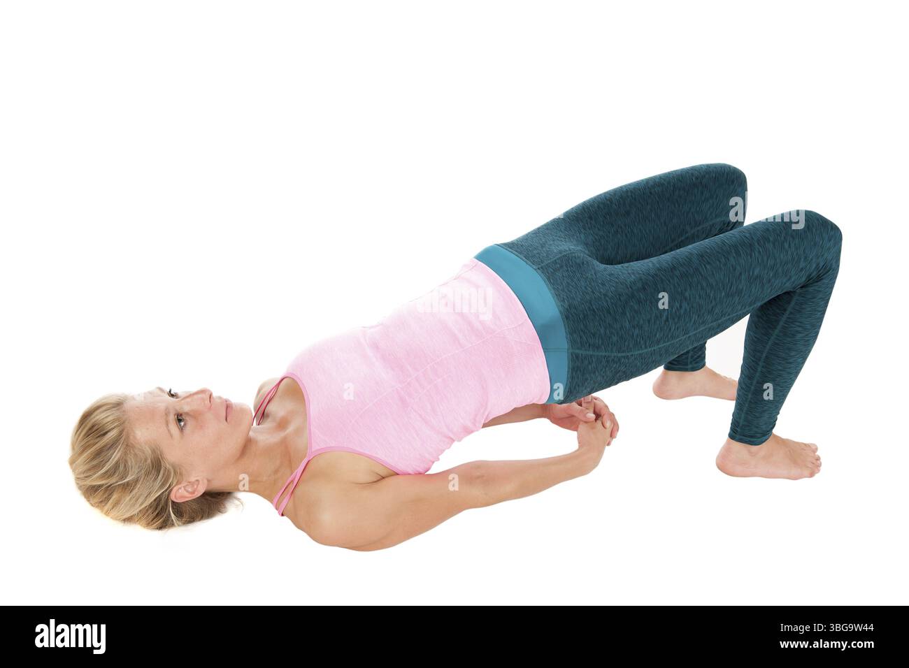 Vista rialzata del profilo laterale a tutto il corpo di una donna bionda di mezza età nello yoga posa il ponte (Sethu Bandhasana) con le braccia appoggiate nuovamente sul pavimento Foto Stock