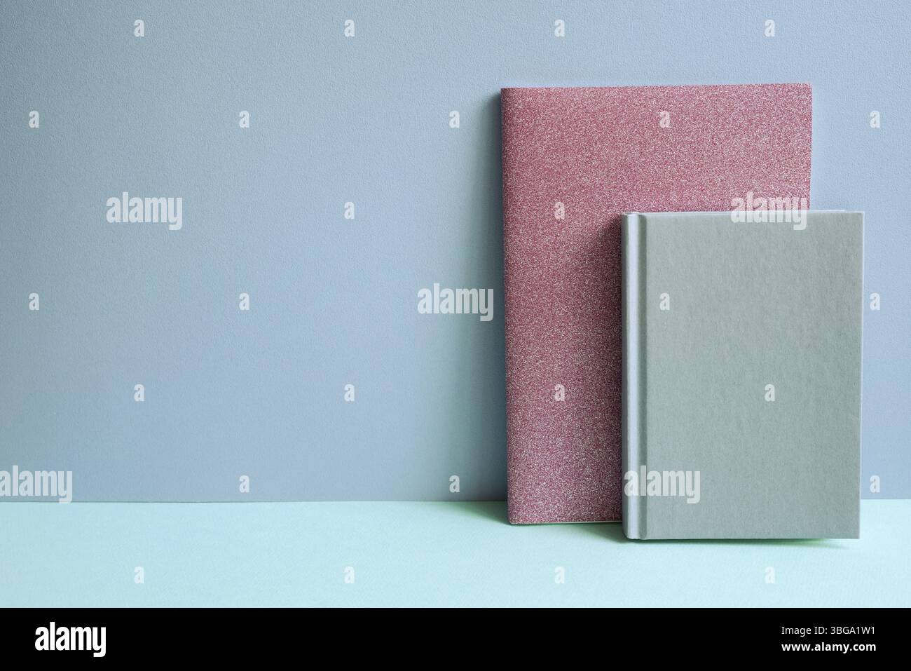 Notebook rosa su scrivania blu. sfondo a parete blu Foto Stock