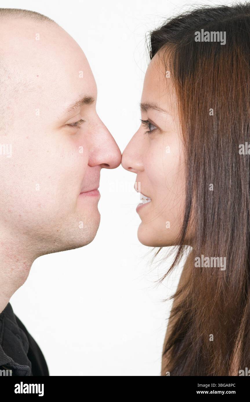 Testa e spalle scattate con il profilo di una giovane coppia naso a naso su sfondo bianco Foto Stock