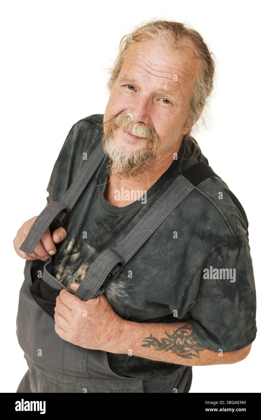 Ritratto della parte superiore del corpo di un uomo anziano con una barba in abiti da lavoro grigio scuro, braccia piegate davanti a uno sfondo bianco, sorridendo contento nel c Foto Stock