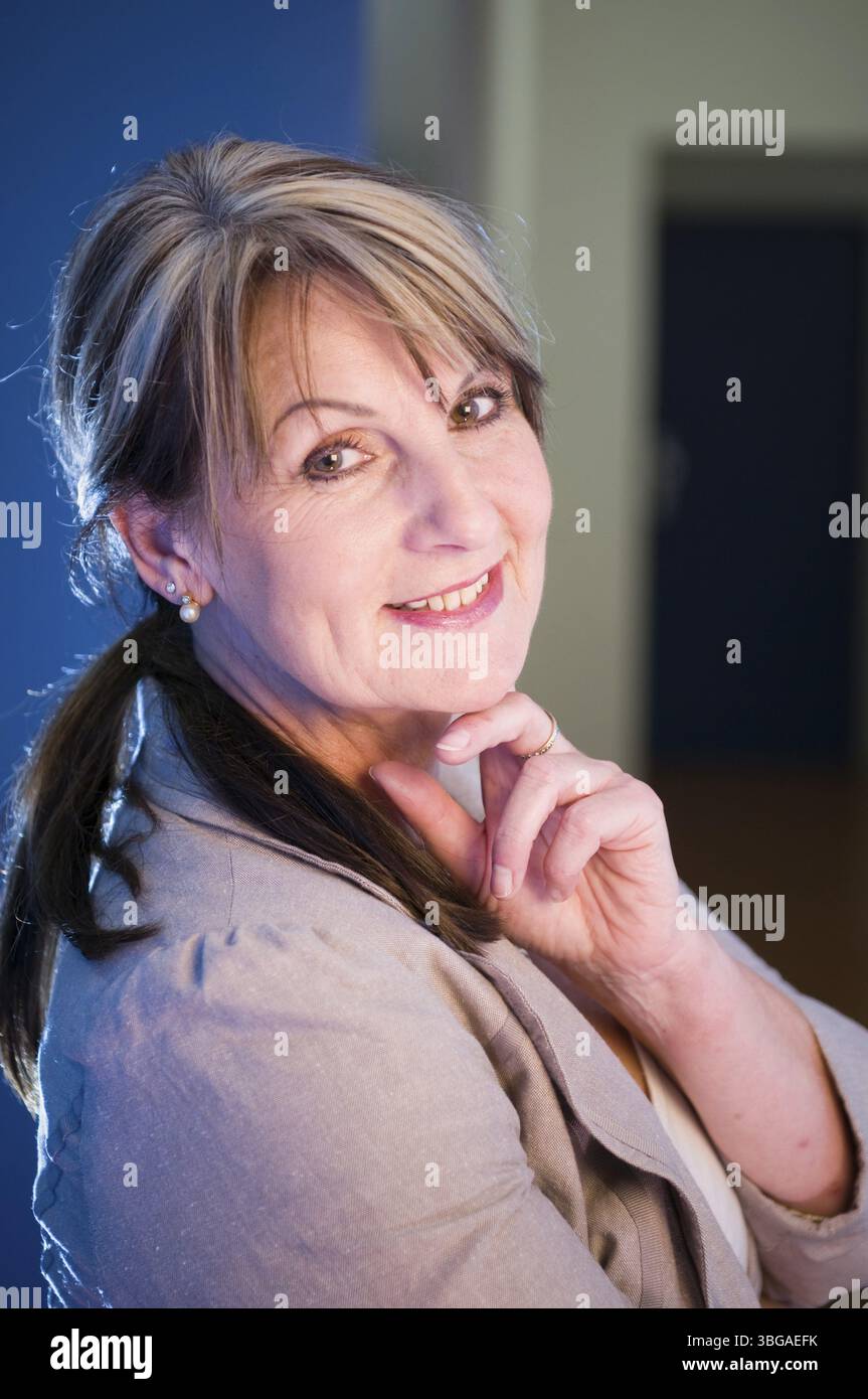 Ritratto laterale superiore del corpo di una donna di mezza età in un vestibolo blu Foto Stock