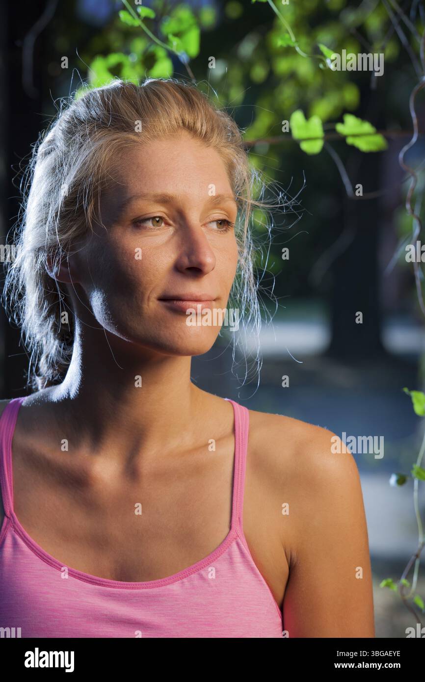 Ritratto della testa laterale di una donna bionda sorridente di mezza età nella luce della finestra laterale Foto Stock