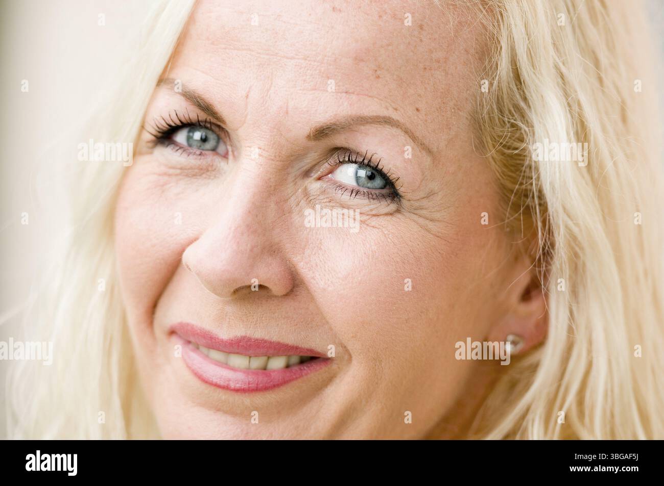 Primo piano di una donna bionda di mezza età che sorride frontalmente nella fotocamera Foto Stock