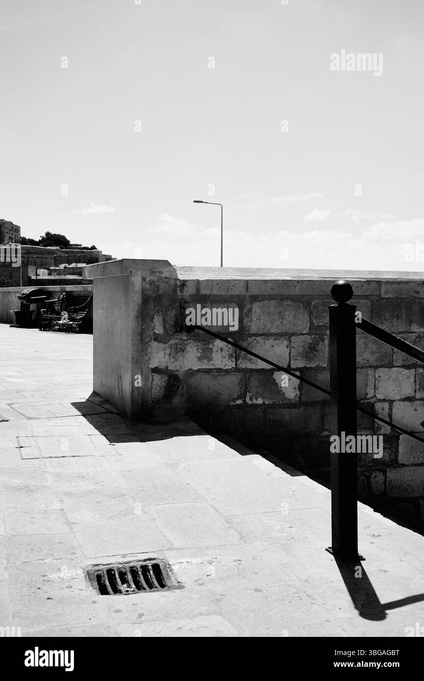 Immagine monocromatica in bianco e nero di gradini con corrimano in metallo nelle giornate di sole nella città mediterranea Foto Stock