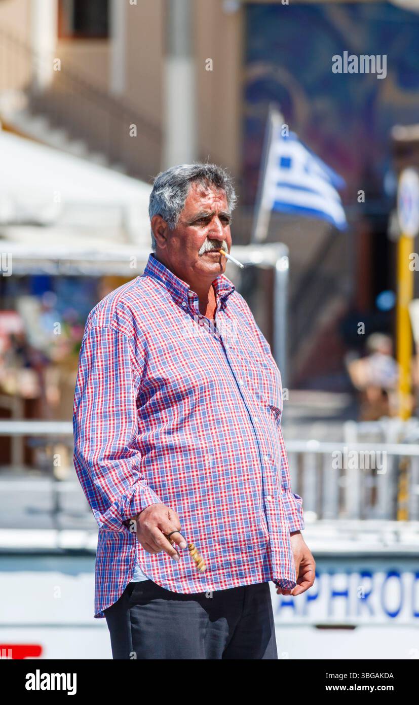 Un uomo greco locale che fuma una sigaretta a Chania (Hania, Xania) Creta, una città portuale sulla costa nord-occidentale di Creta, la più grande isola greca Foto Stock