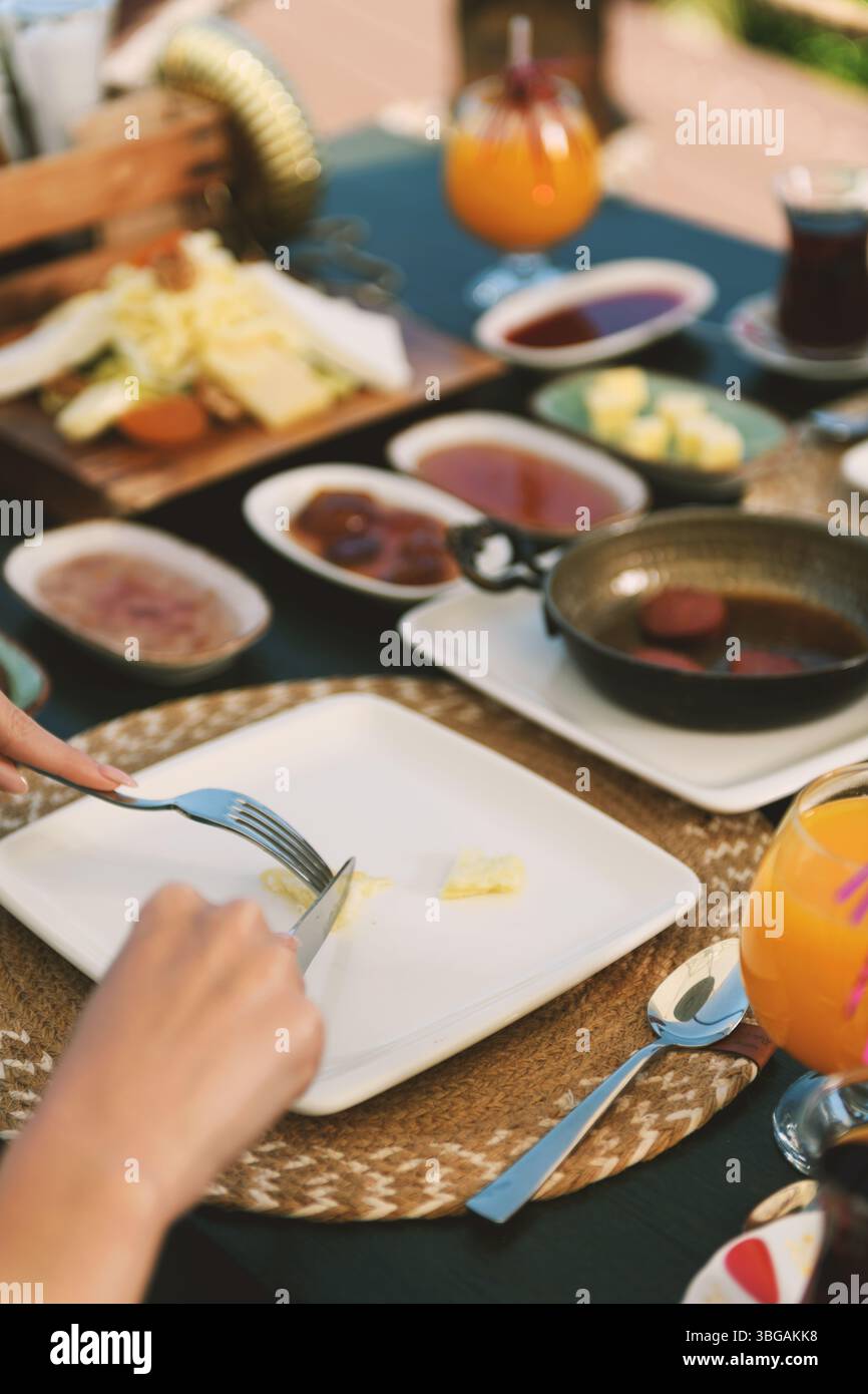 Primo piano dettagliato di una donna bruna tagliata con cura in una soffice omelette durante la colazione. Foto Stock