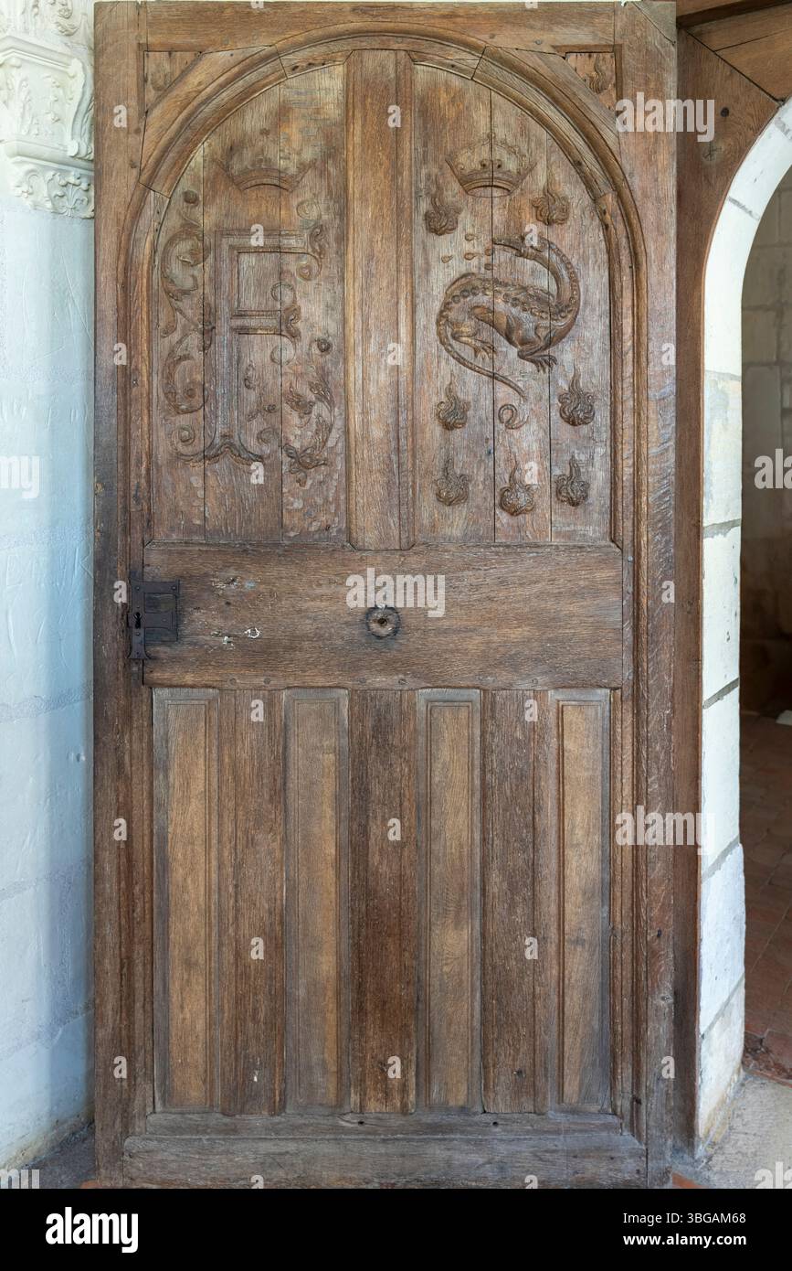 La porta in legno decorata presenta elaborate sculture in salamandra e monogrammi reali che mostrano l'artigianato rinascimentale a Chambord. Foto Stock
