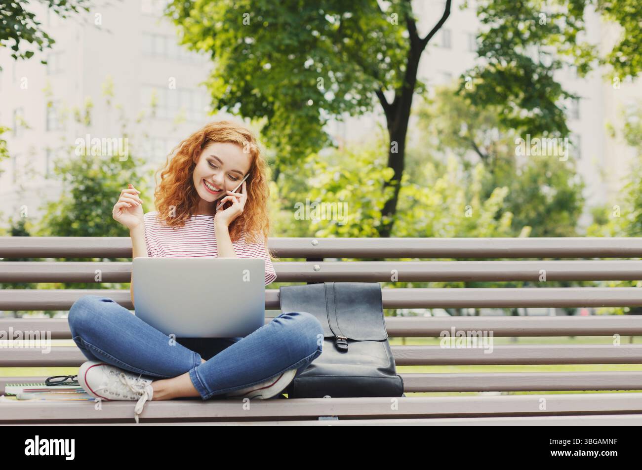 Donna che lavora con un laptop e parla con il suo smartphone Foto Stock