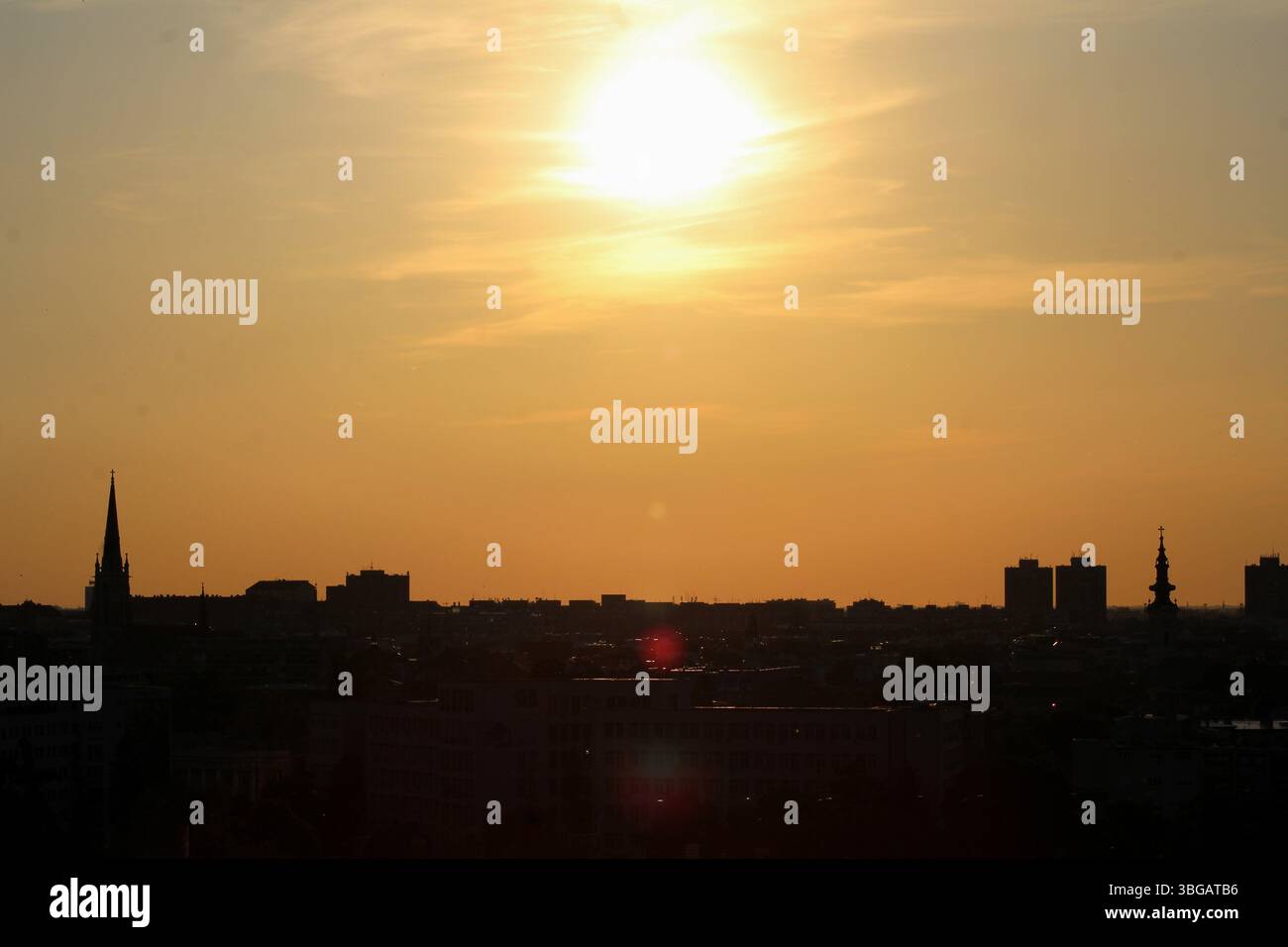 Sagome dello skyline di Novi Sad durante l'ora d'oro, con guglie ed edifici della chiesa sotto un cielo luminoso al tramonto. Foto Stock Sagome dello skyline di Novi Sad durante l'ora d'oro, con guglie ed edifici della chiesa sotto un cielo luminoso al tramonto. Foto Stock