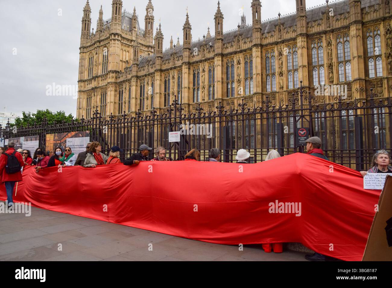 Londra, Regno Unito. 4 giugno 2025. I manifestanti detengono un lungo tessuto rosso fuori dalle camere del Parlamento che simboleggia le "linee rosse” attraversate da Israele, durante una manifestazione pro-Palestina. I manifestanti pro-palestinesi hanno organizzato una protesta chiedendo un embargo sulle armi contro Israele, che gli aiuti vengono erogati alla popolazione affamata di Gaza e che Israele interrompe i suoi attacchi. Credito: SOPA Images Limited/Alamy Live News Foto Stock