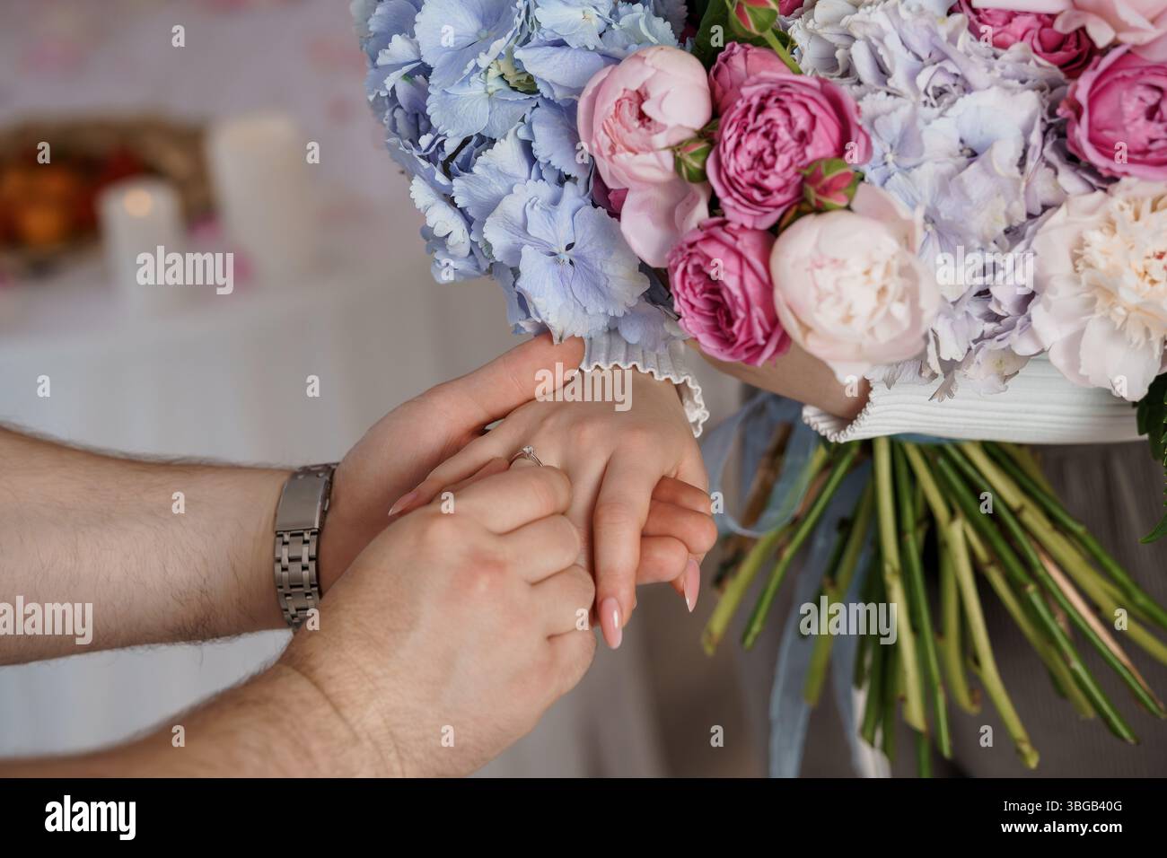 Uno scatto ravvicinato cattura una coppia amorosa che si scambia i voti, le mani che espongono le fedi nuziali su un lussureggiante bouquet di ortensie pastello, simboleggiando l'impegno Foto Stock