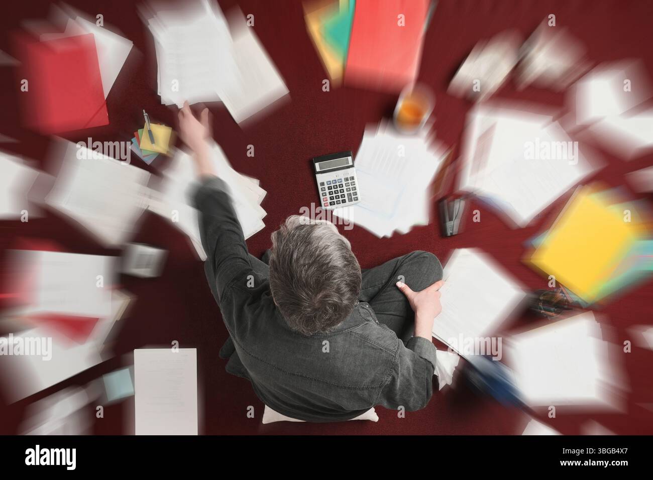 Contabilità ed elaborazione di documenti stressanti. Uomo che svolge un lavoro impegnativo con le tasse, foto dall'alto con effetto zoom sfocatura Foto Stock