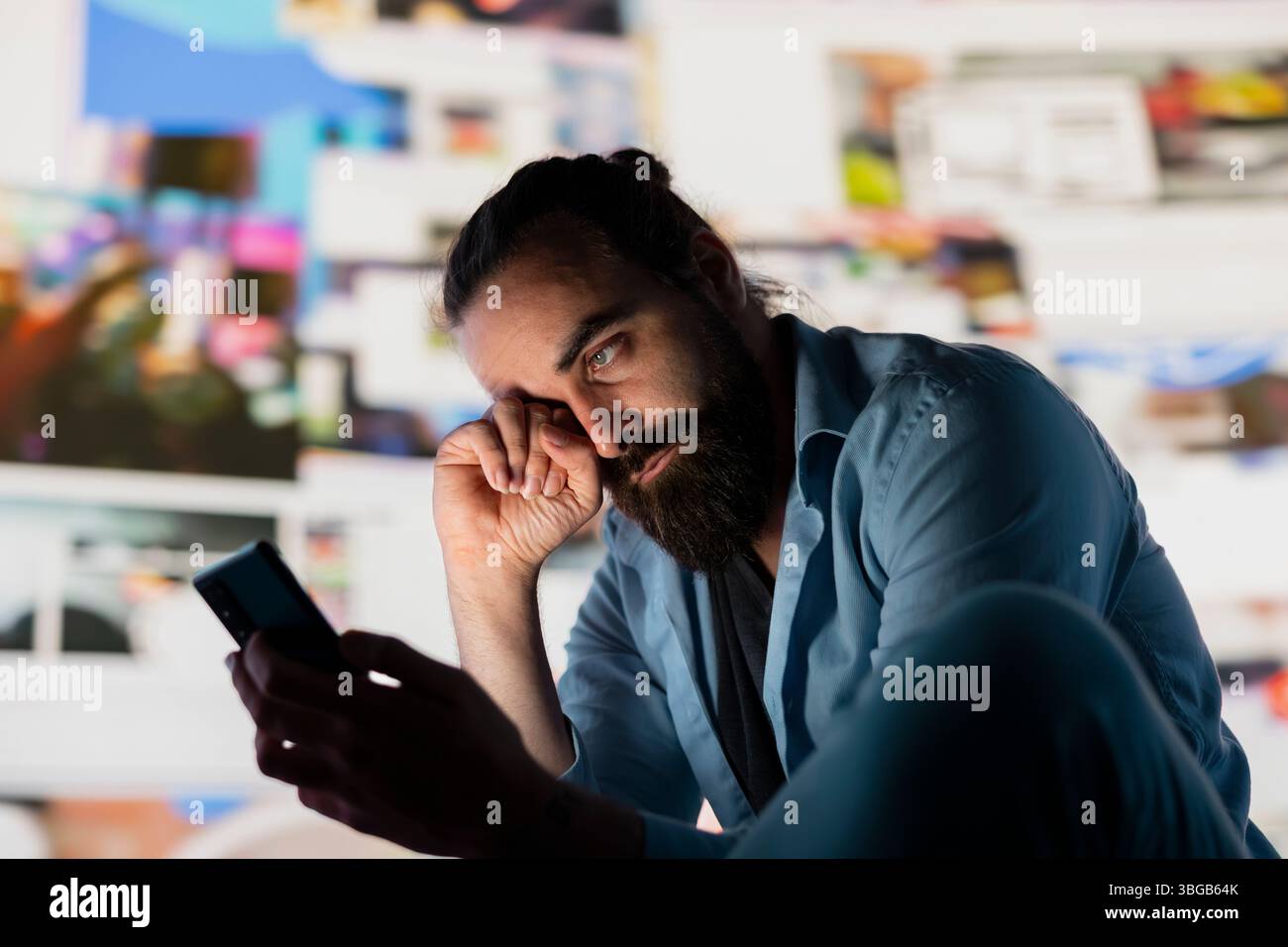 L'uomo in difficoltà soffre di un danno da ansia sociale dovuto all'uso ossessivo dei social media. Giovane adulto sopraffatto da informazioni eccessive e sovraccarico o cyberbullismo che influenzano la sua autostima. Foto Stock