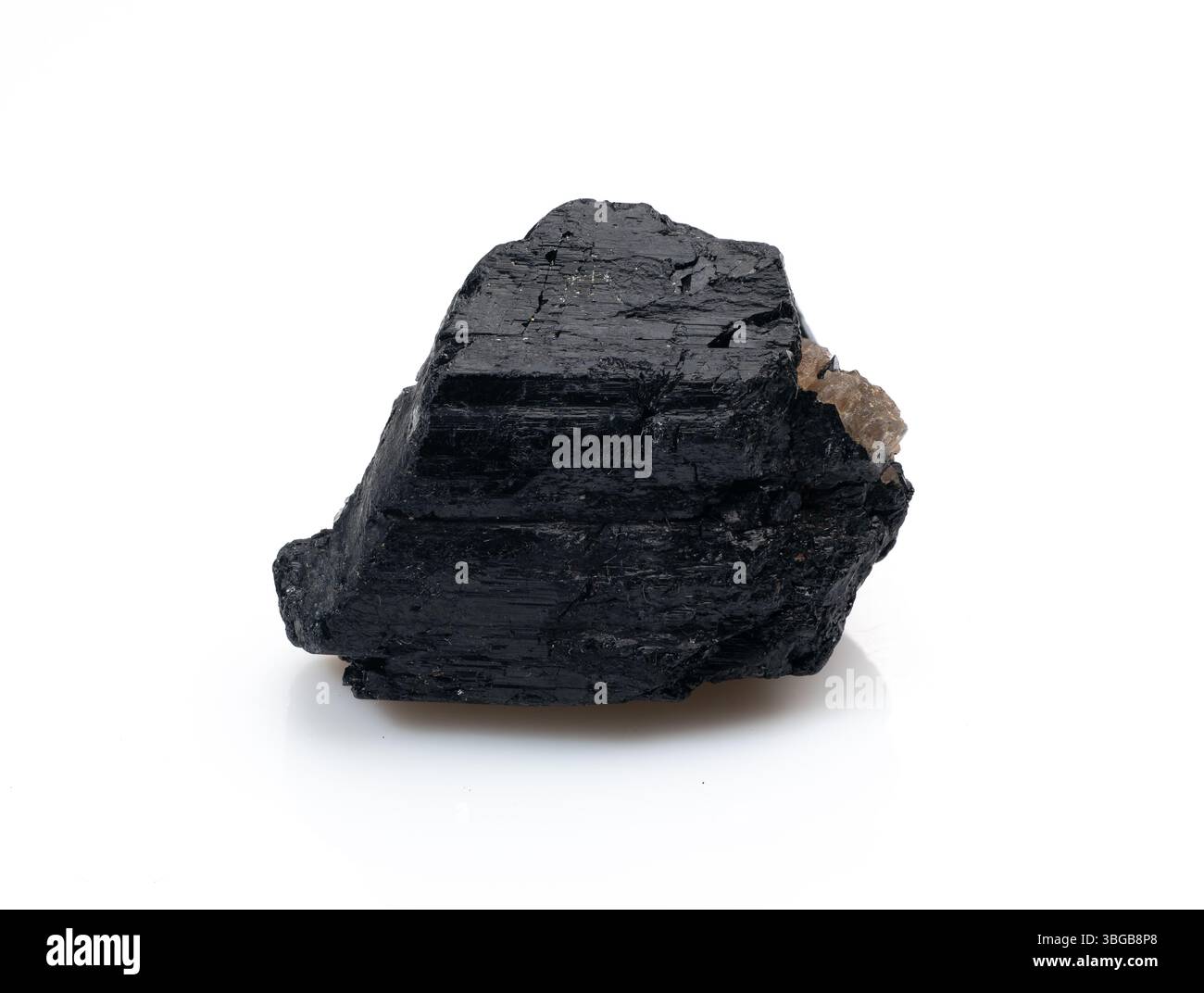 Questa immagine mostra un cristallo di tormalina nera ruvida, non lucidata, che mostra la sua forma naturale e la sua lucentezza metallizzata scura su un dorso bianco pulito Foto Stock