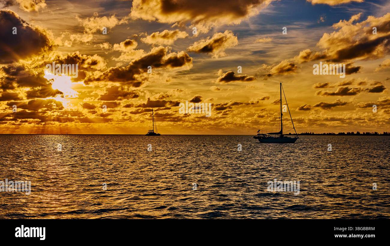 Tramonto dorato sul mare nelle isole Abacos delle Bahamas con barche a vela sullo sfondo. Foto Stock