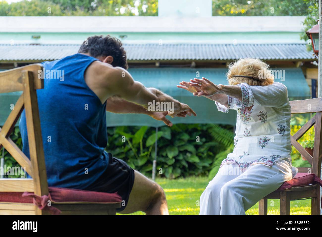 Fisioterapista che assiste una donna anziana con esercizi di riabilitazione in un vivace giardino domestico, migliorando la salute e la mobilità e promuovendo al contempo una guarigione Foto Stock