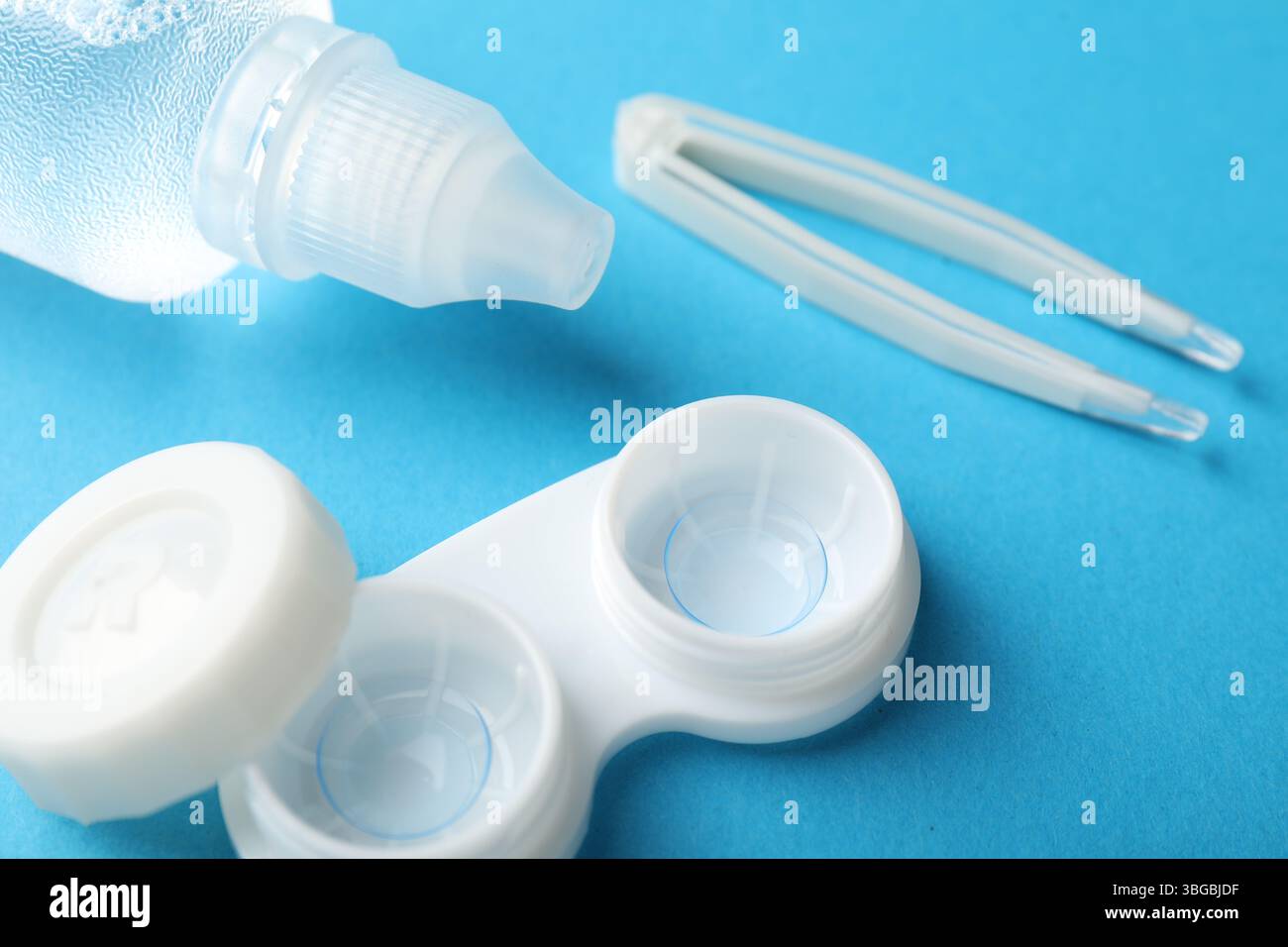 Lenti a contatto in astuccio, soluzione e pinzette su sfondo blu, primo piano Foto Stock
