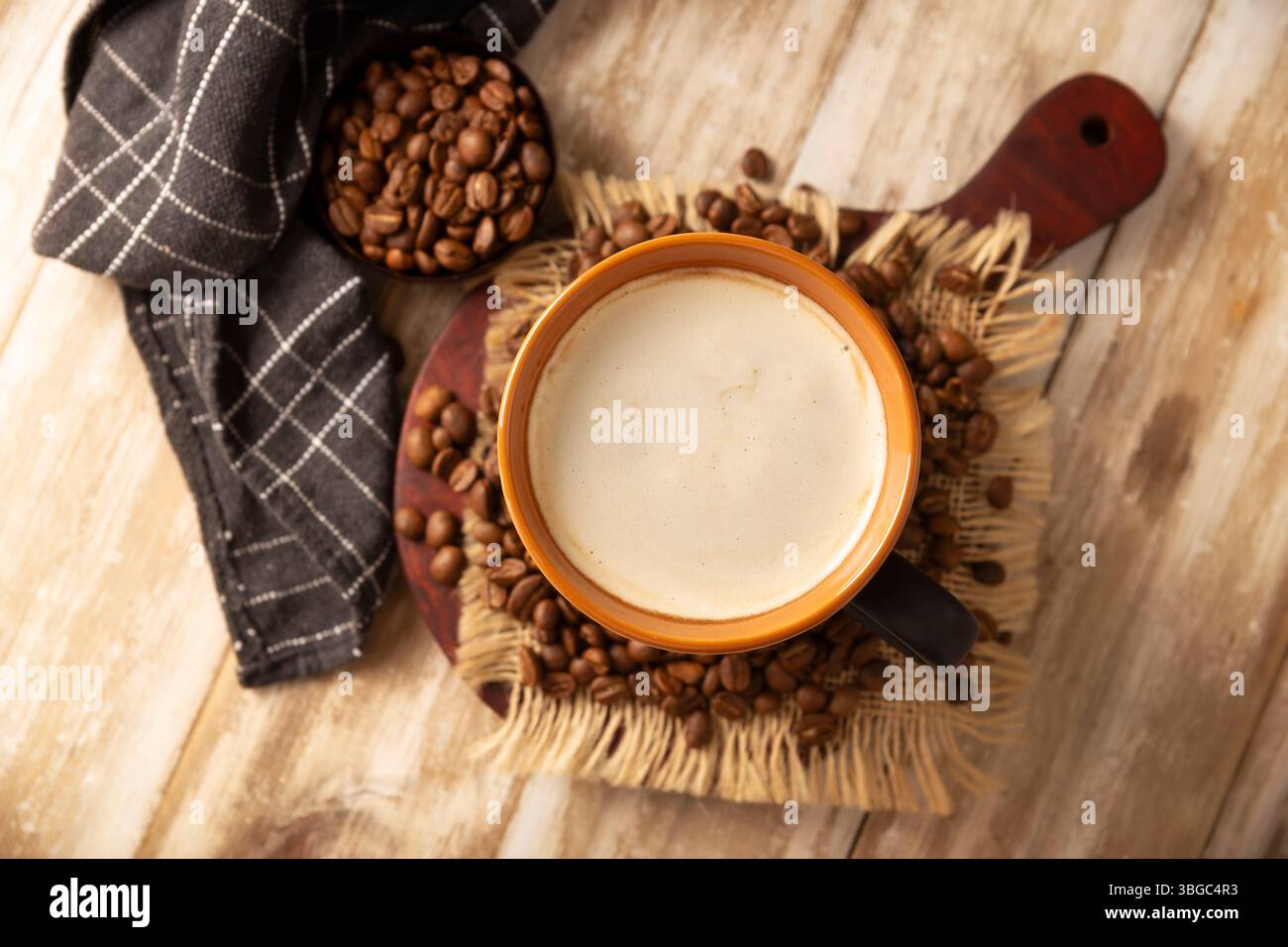 Caffè bianco piatto in una tazza nera con chicchi di caffè su un tavolo in legno rustico, pressa francese sullo sfondo. Foto Stock